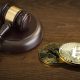 A judge’s gavel beside two physical Bitcoin tokens.