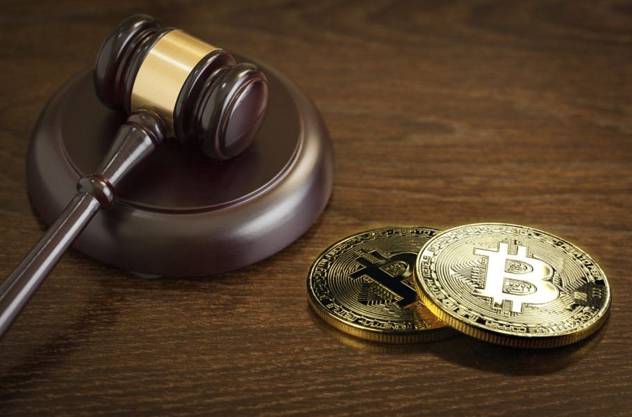 A judge’s gavel beside two physical Bitcoin tokens.