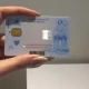 A hand holding an Iranian national ID card with an embedded chip.