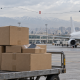AI-generated editorial composite of phone shipments at a Tehran airport, with an interrupted Oman-to-Iran flight route overlay.