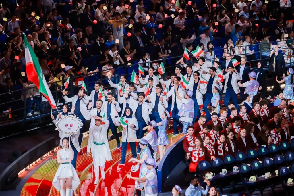 Group waving Iranian flags beside arena seating.