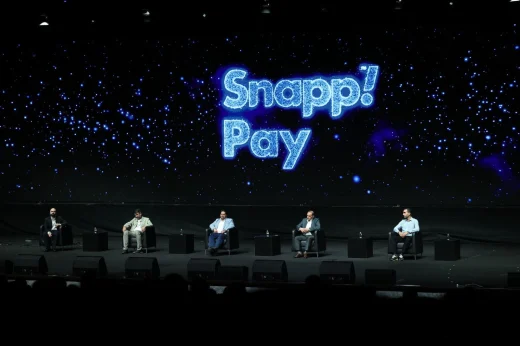 Five seated speakers take part in a panel in front of a blue SnappPay backdrop.