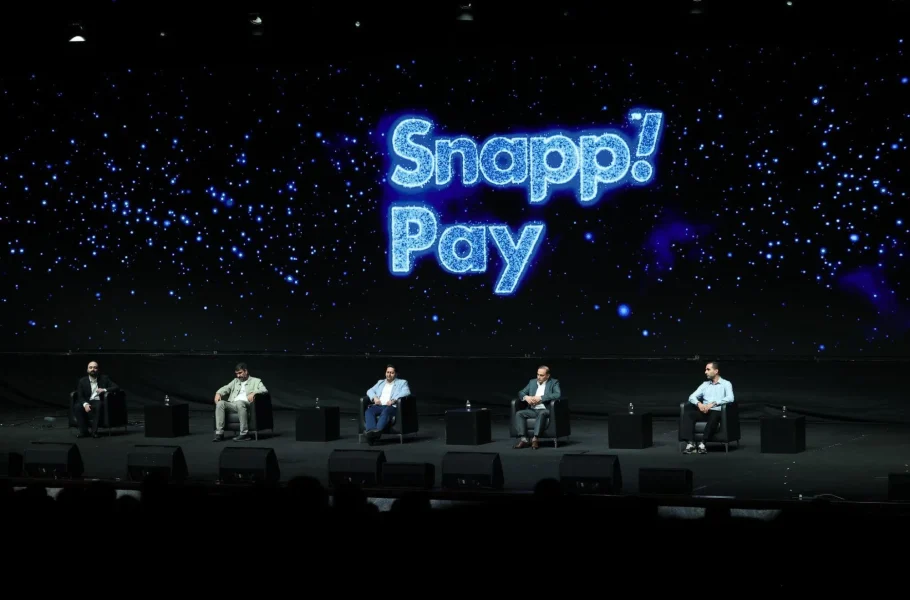 Five seated speakers take part in a panel in front of a blue SnappPay backdrop.