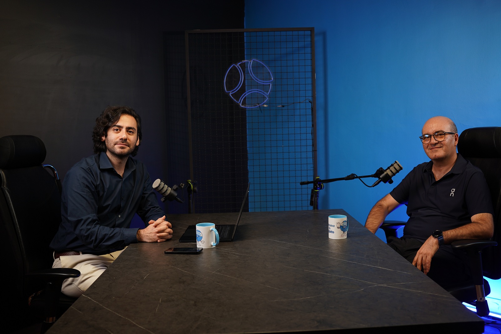 Digipay CEO Omid Torabi, right, seated opposite an interviewer at a table with microphones.
