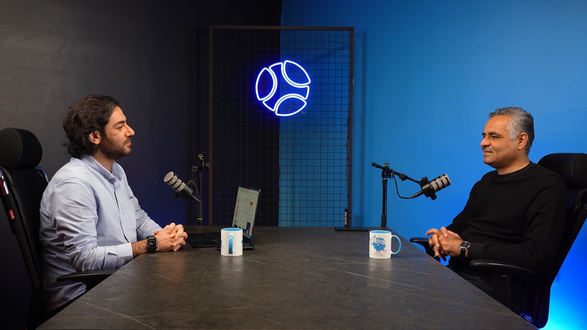 Azizollahi and an interviewer seated across a table with microphones in Digiato’s studio.