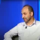 Mohammad Sarafraz seated against a blue studio backdrop.