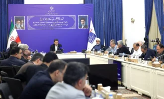 Sattar Hashemi sits at the head of a meeting table with officials seated around him.