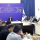 Sattar Hashemi sits at the head of a meeting table with officials seated around him.