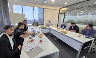 Seven people seated around a conference table in an office meeting room.