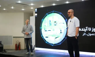 Two people stand on a stage in front of a large presentation screen.