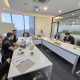 Seven people seated around a conference table in an office meeting room.
