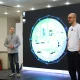 Two people stand on a stage in front of a large presentation screen.