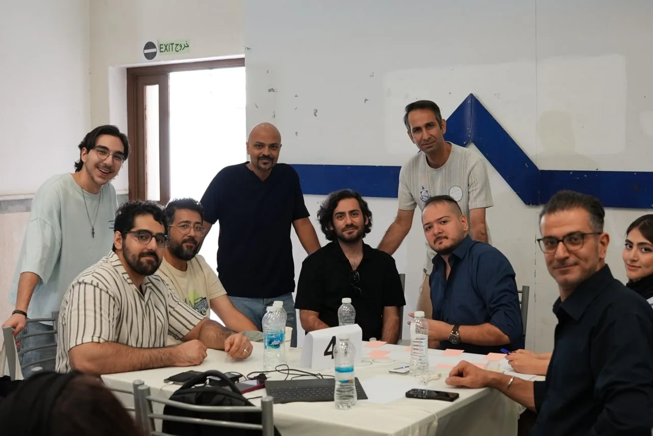 A group poses around a table with notes, water bottles and computer equipment.